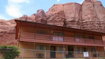 A two-story building with a balcony on the second floor, surrounded by red rock formations.