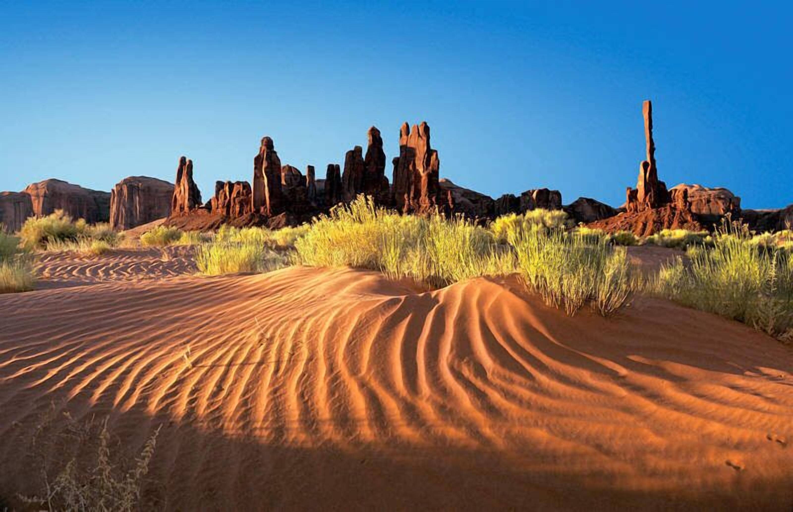 A desert landscape with prominent rock formations and sand dunes.