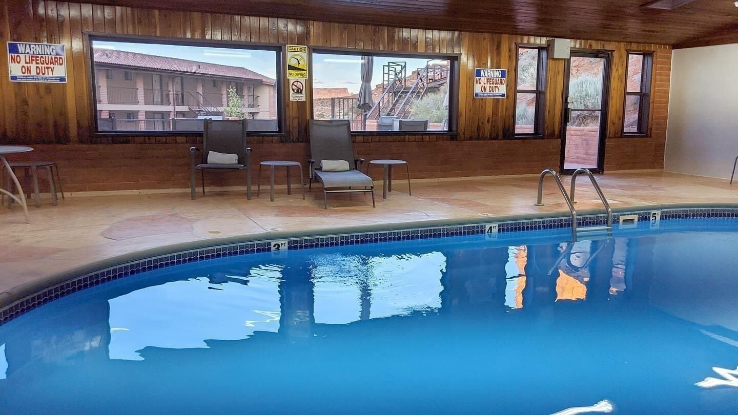 An indoor swimming pool with wooden walls, a lifeguard chair, and warning signs.
