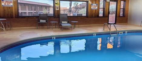 An indoor swimming pool with wooden walls, a lifeguard chair, and warning signs.
