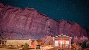 A house with a large rock formation in the background.