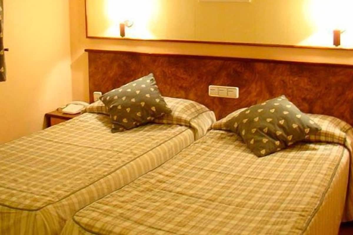 A double bed with a headboard, two pillows, a bedside table, and a nightstand.