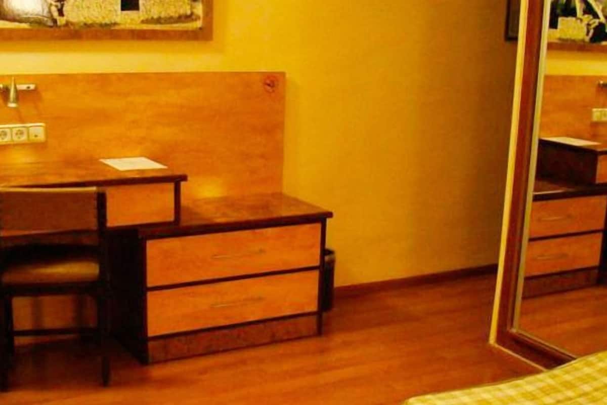 A compact room with a wooden desk, a chair, a mirror, and a television.