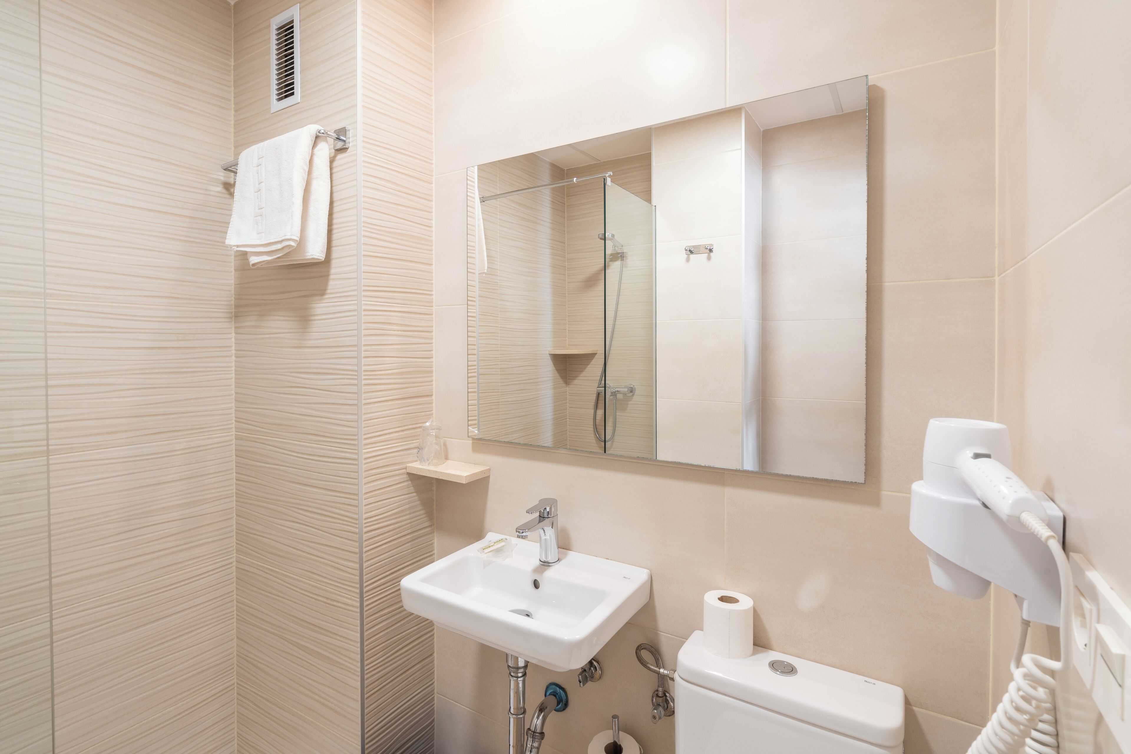Un baño moderno con cabina de ducha de vidrio, lavamanos, inodoro y espejo.