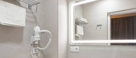 A modern bathroom with a toilet, sink, and hairdryer mounted on the wall.