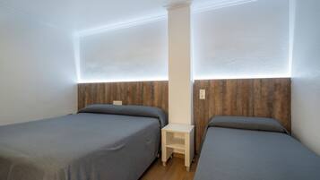 A room with two single beds, a small bedside table, and a wooden headboard.