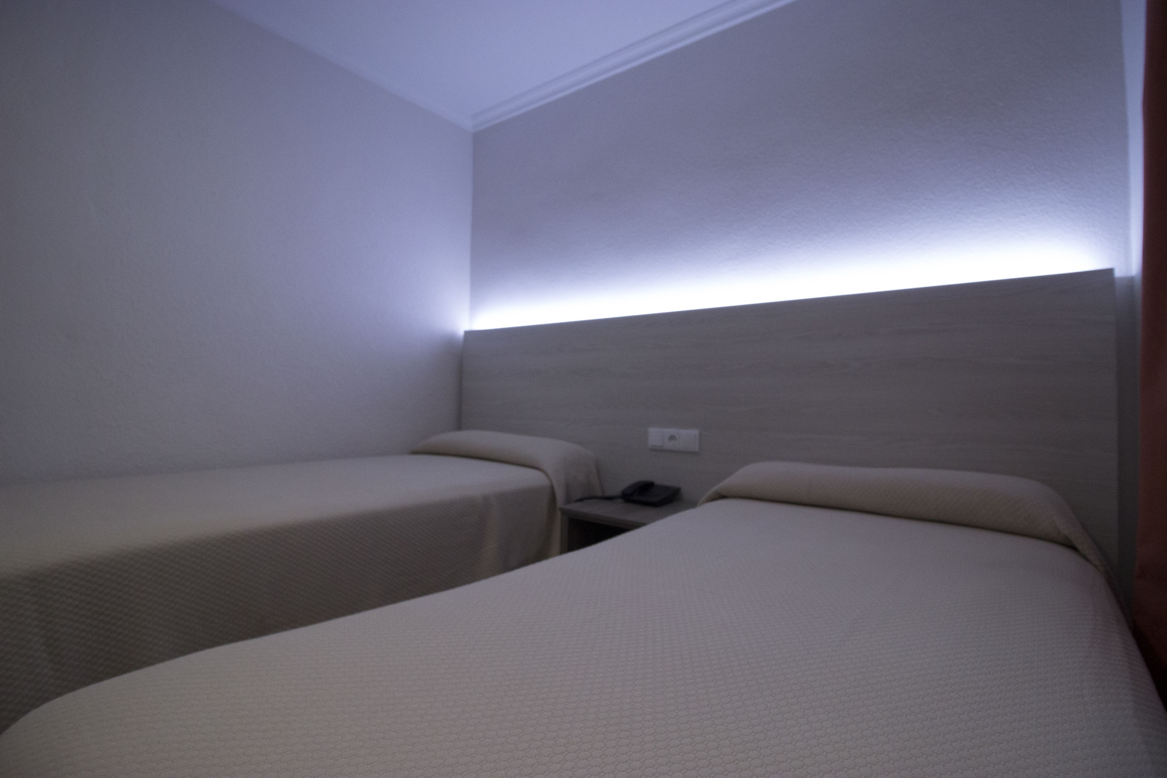Ein Hotelzimmer mit zwei Einzelbetten, einem Nachttisch und einem an der Wand befestigten Telefon.