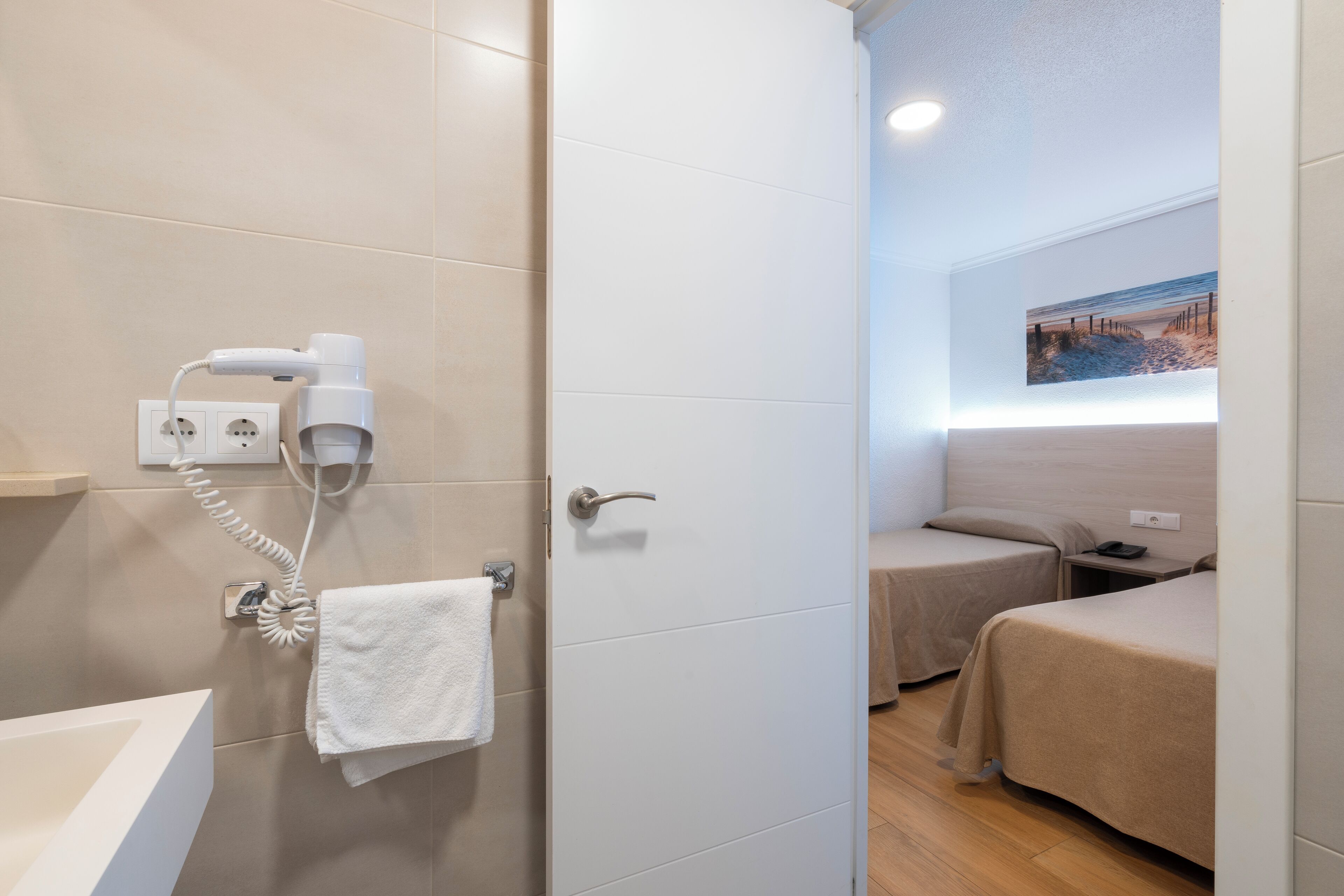 Habitación de hotel con baño, secador de pelo, toalla y cama.