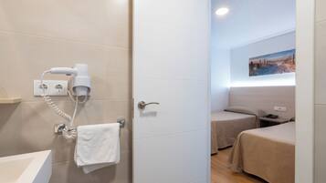 Habitación de hotel con baño, secador de pelo, toalla y cama.