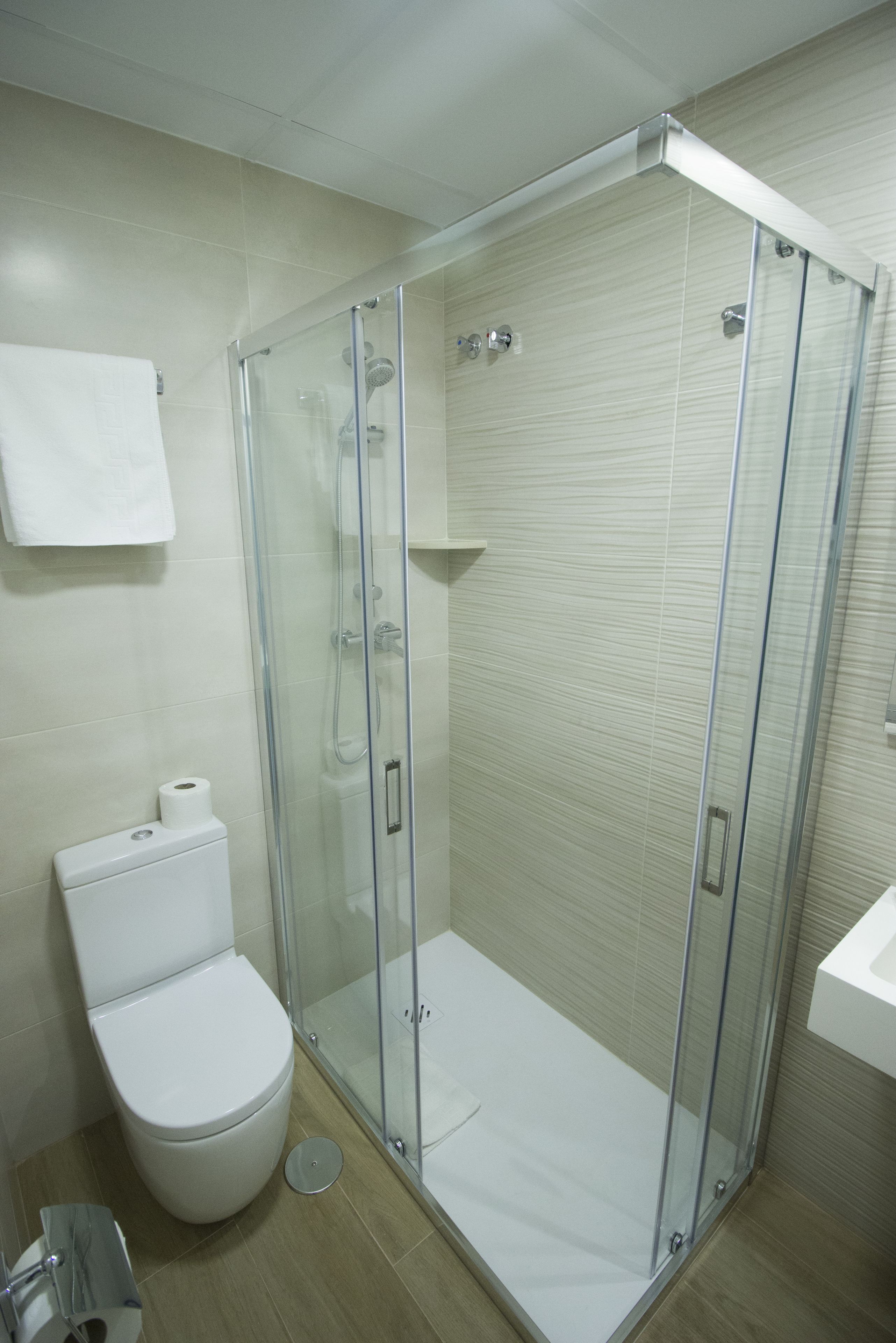 Een moderne badkamer met een douchecabine van glas, een toilet en een wastafel.
