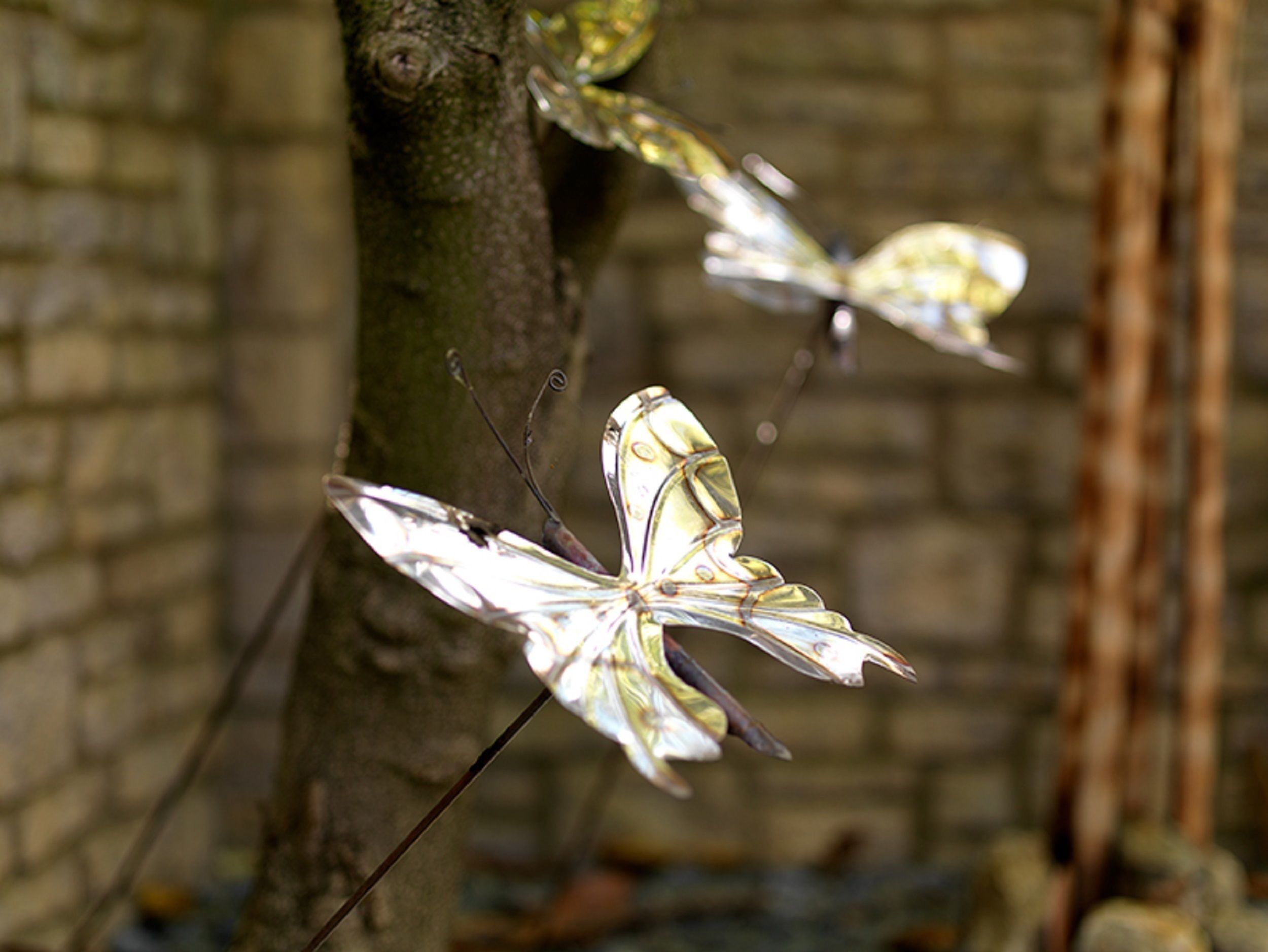 Una escultura de mariposa de cristal sobre una rama de árbol.