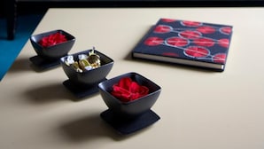 Un salón con un sofá, cojines y una mesa con cuencos y un libro.