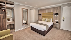 Camera d'albergo moderna con un letto grande, un armadio a muro, un bagno con uno specchio e un comodino con una lampada.