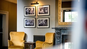 Una stanza con due poltrone gialle, un camino e quattro fotografie incorniciate appese al muro.
