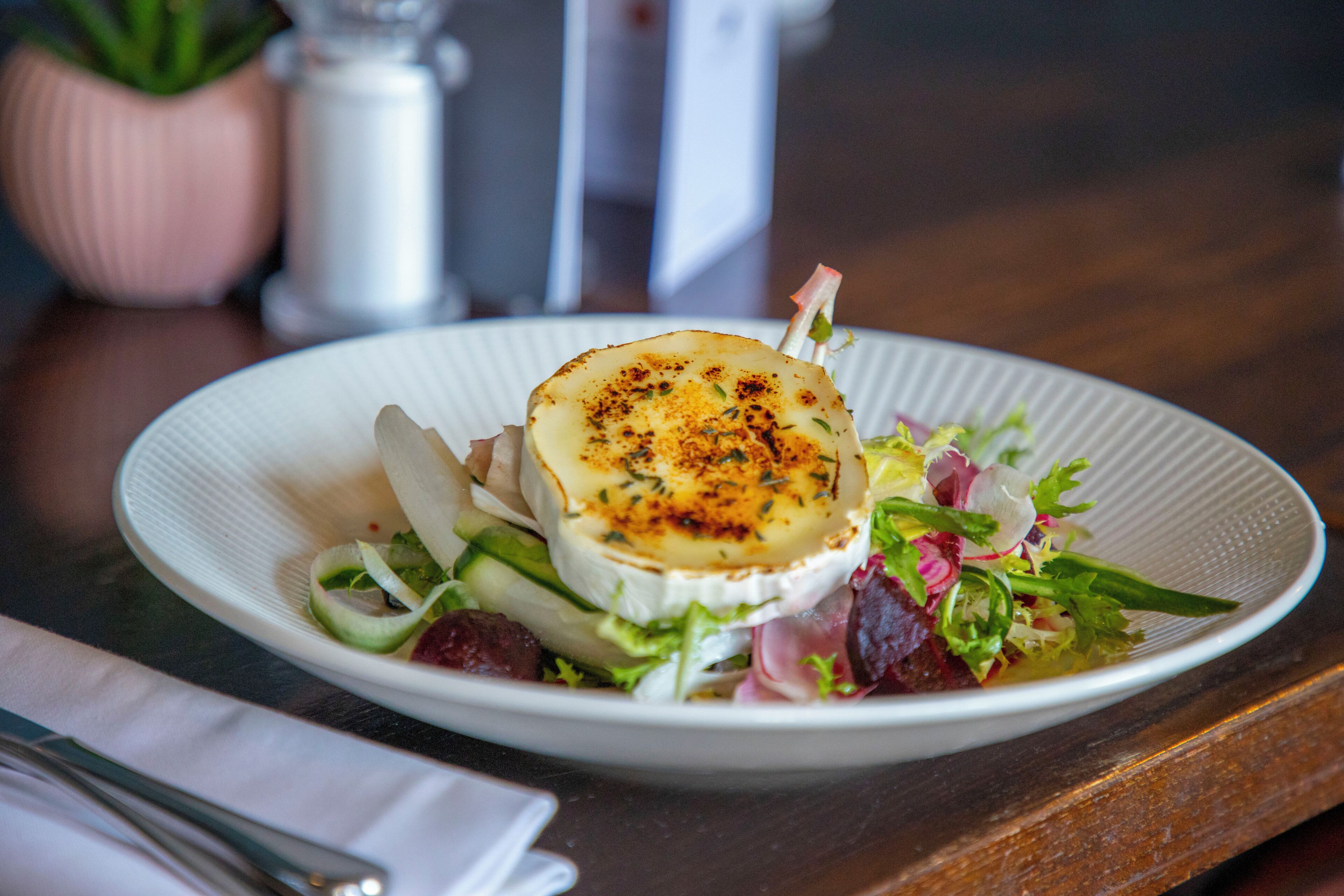 A plate of food with a creamy topping, accompanied by a salad.