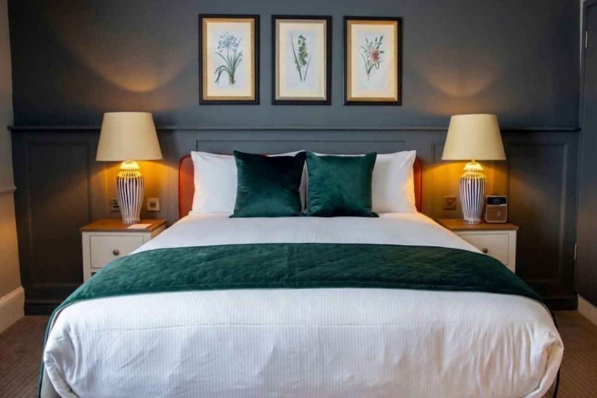 A hotel room with a large bed, two bedside tables, and wall-mounted lamps.
