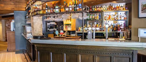 Una zona de bar con varias estanterías llenas de diferentes botellas y vasos.