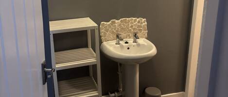 A bathroom with a white sink, a mirror, and a tiled floor.