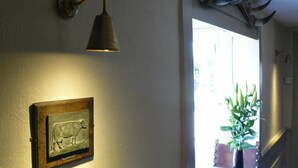 A wall-mounted light fixture, a framed cow sculpture, and a plant in a vase.