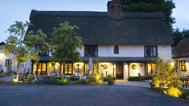 A traditional building with a tiled roof, multiple windows, and a well-lit entrance.