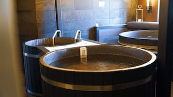 Un espacio de spa con dos tinas de madera grandes y un banco.