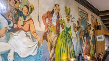 A mural with various figures and a table with candles.