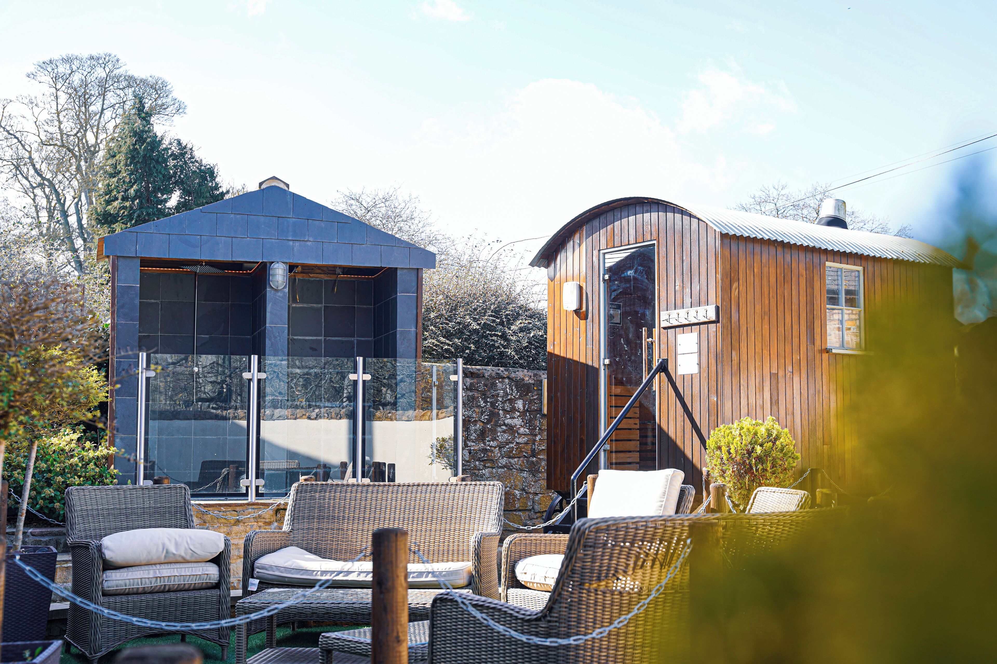 A modern outdoor seating area with wicker furniture and a glass enclosure.