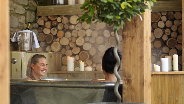 Un área de spa con pared de piedra, troncos de madera y velas.