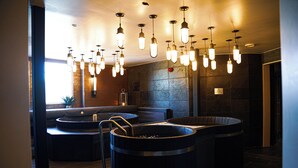 Un área de spa con varios jacuzzis y asientos, iluminada por lámparas colgantes.