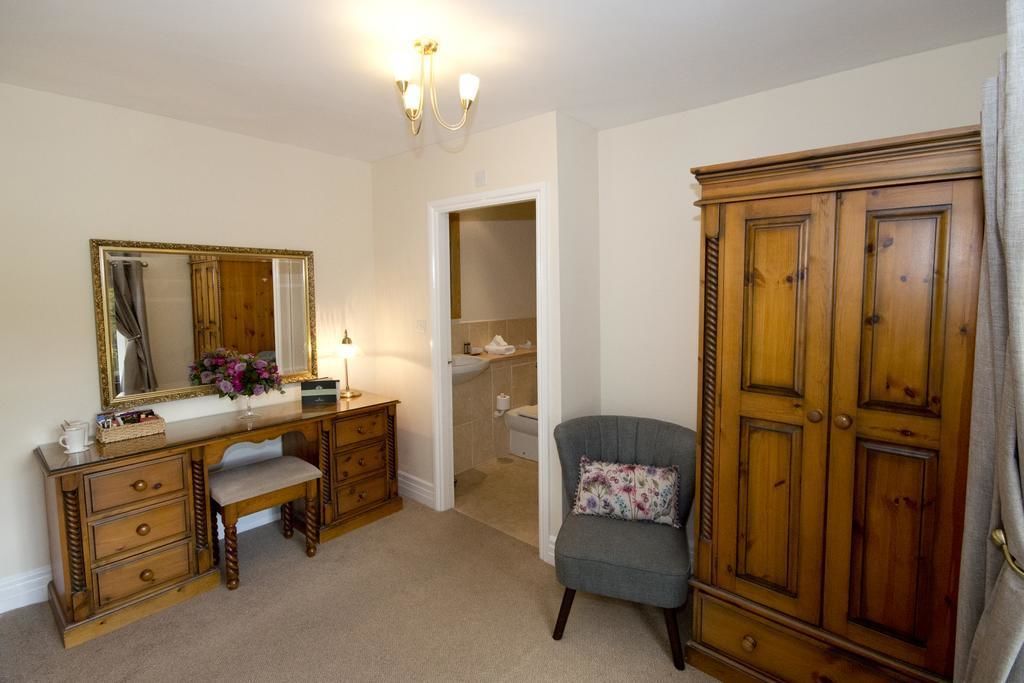 Quarto com penteadeira de madeira, espelho, cadeira e guarda-roupa.