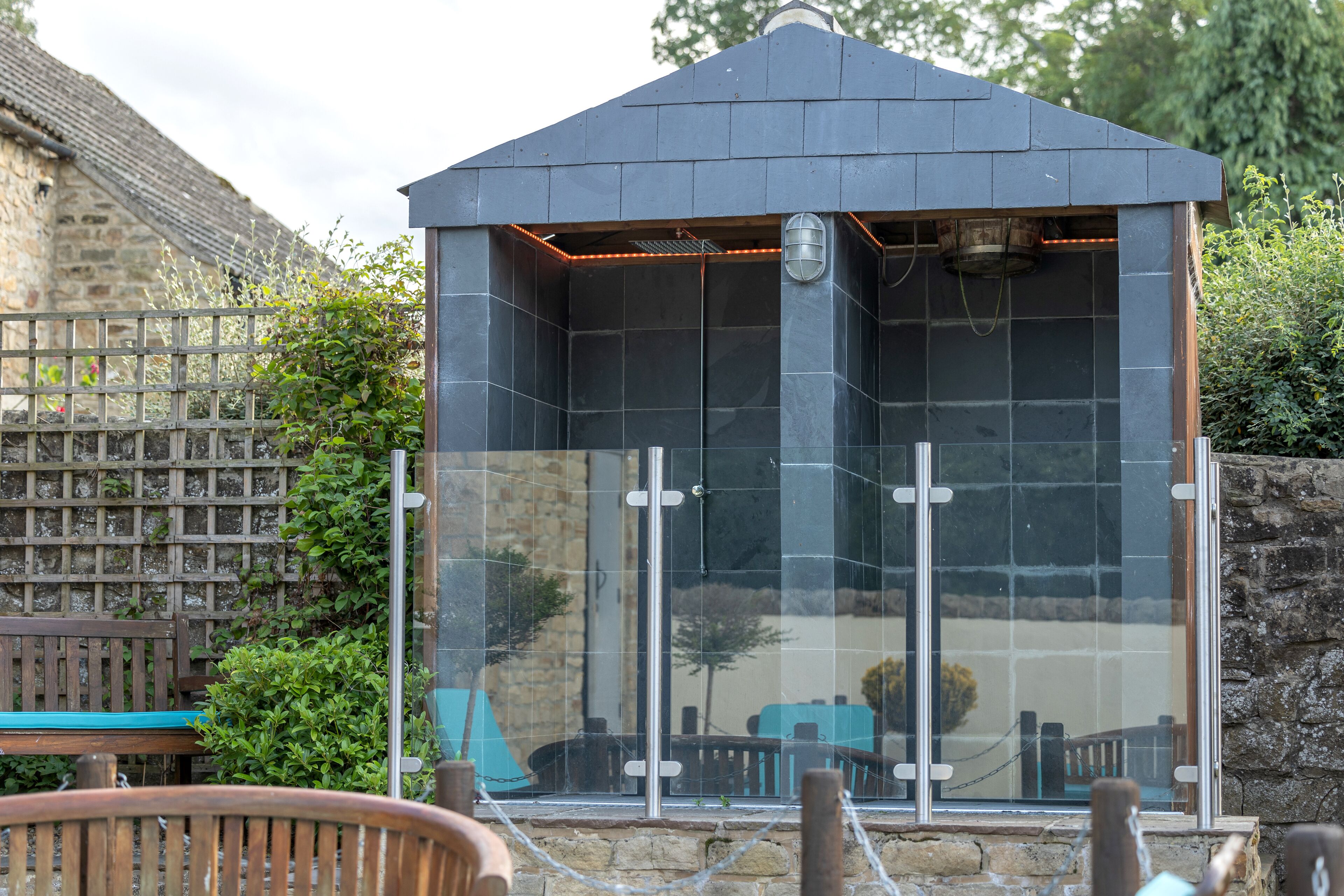 A modern building with a dark roof, large glass windows, and a metal railing.