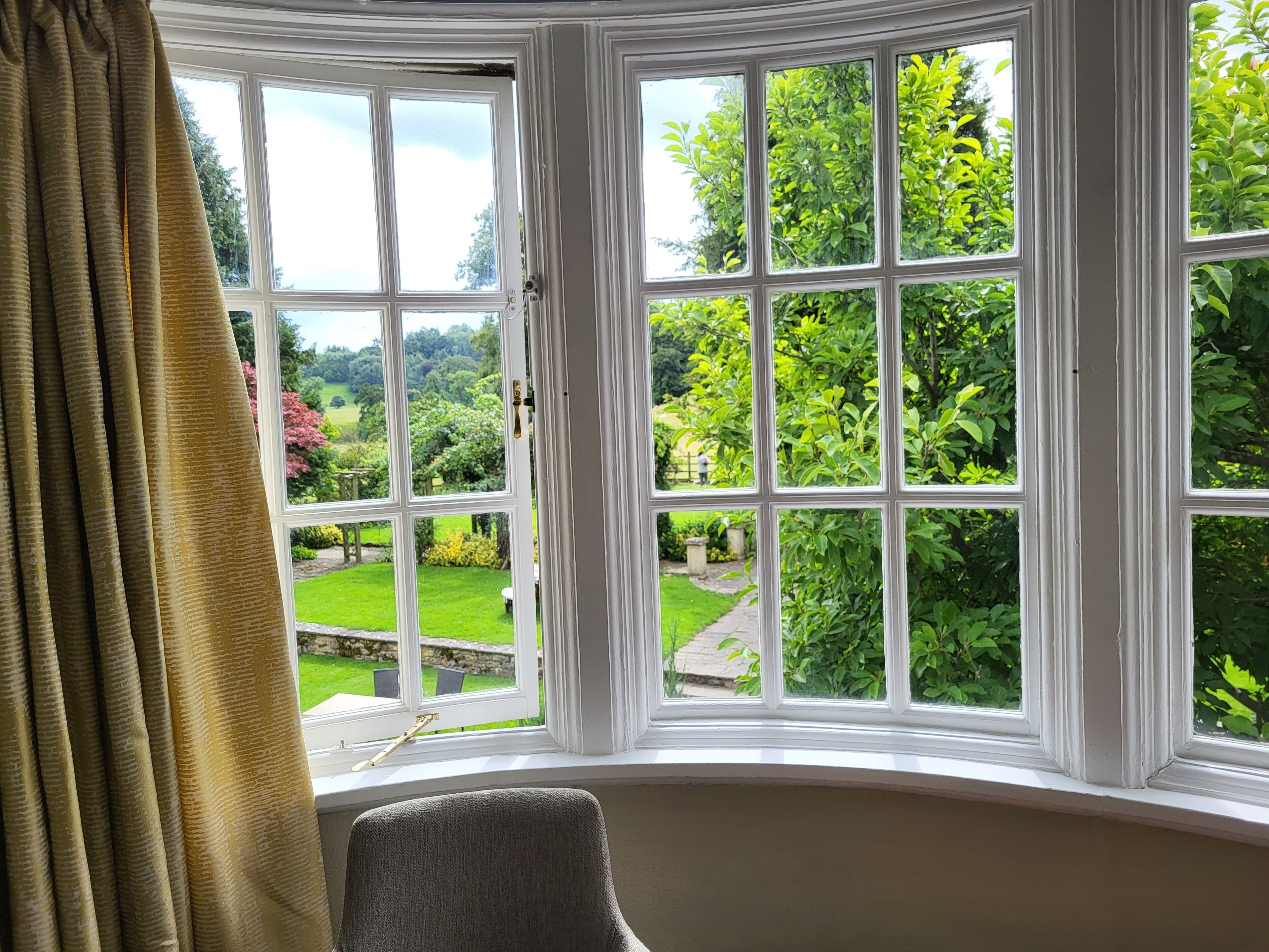 A room with a bay window overlooking a garden.