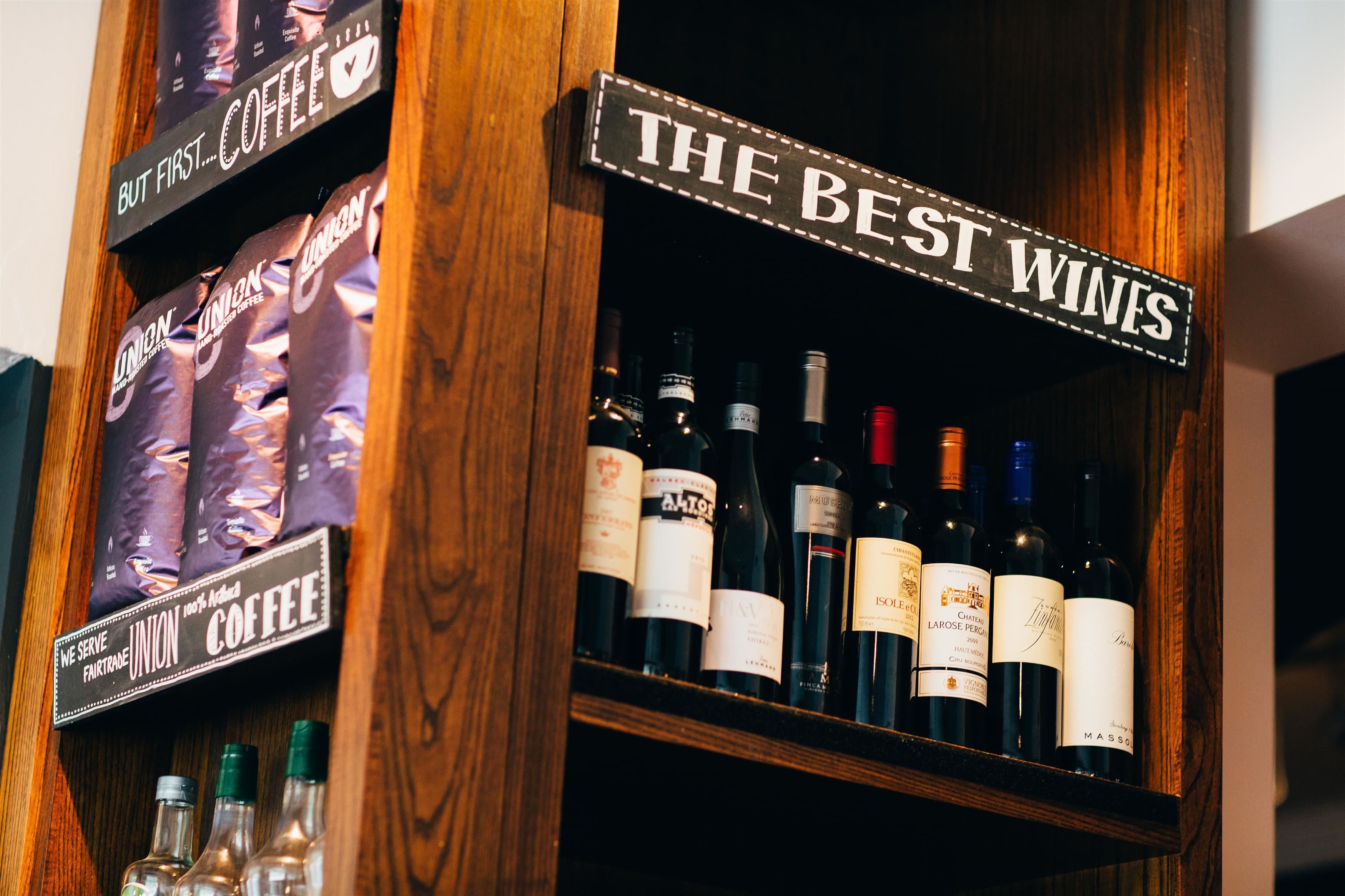 A shelf with coffee bags and wine bottles, labeled "The Best Wines" and "Union Coffee."