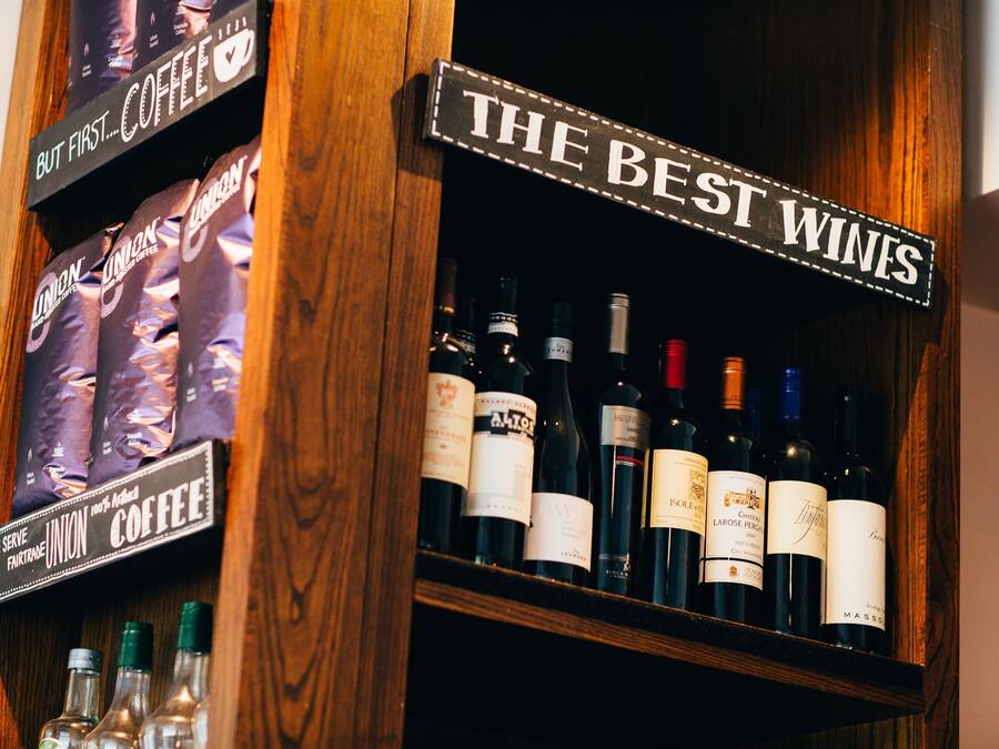 Une étagère avec des sacs de café et des bouteilles de vin, étiquetées « Les meilleurs vins » et « Café Union ».