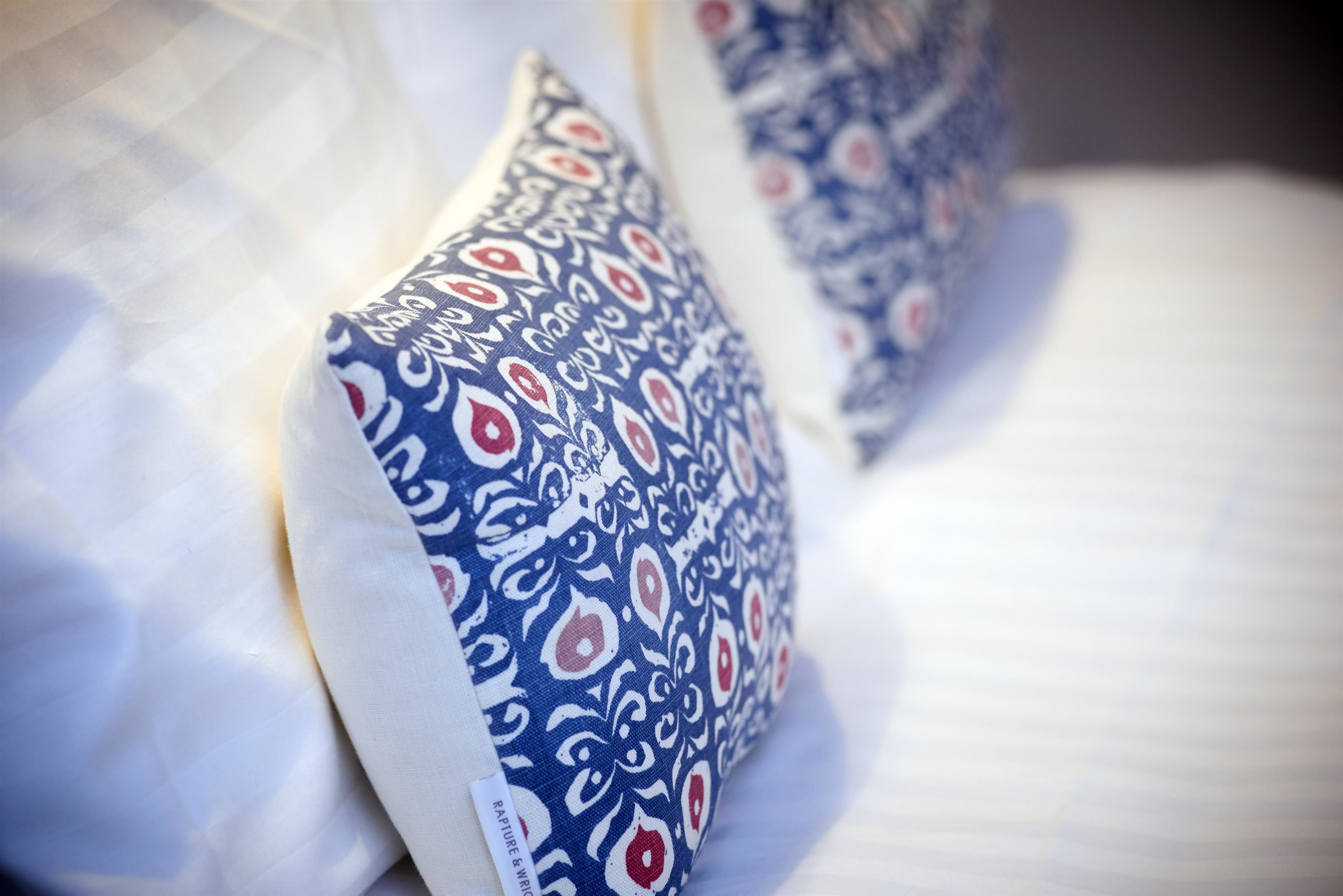 Un gros plan d’un lit avec une literie blanche et des coussins à motifs bleus.