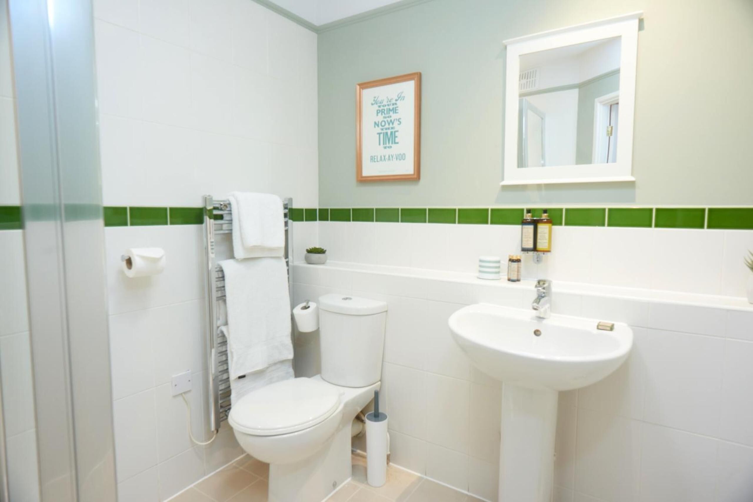 Un baño con inodoro, lavabo y una cita enmarcada en la pared.