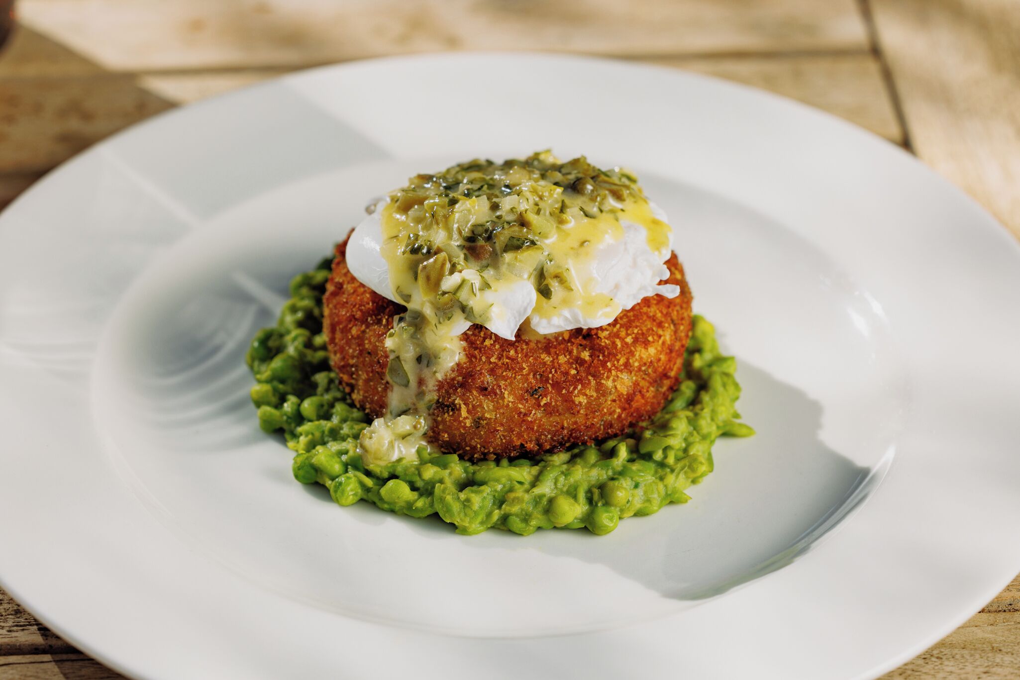 A white plate with a food item on top of a green base, possibly a dish with a creamy sauce and green topping.