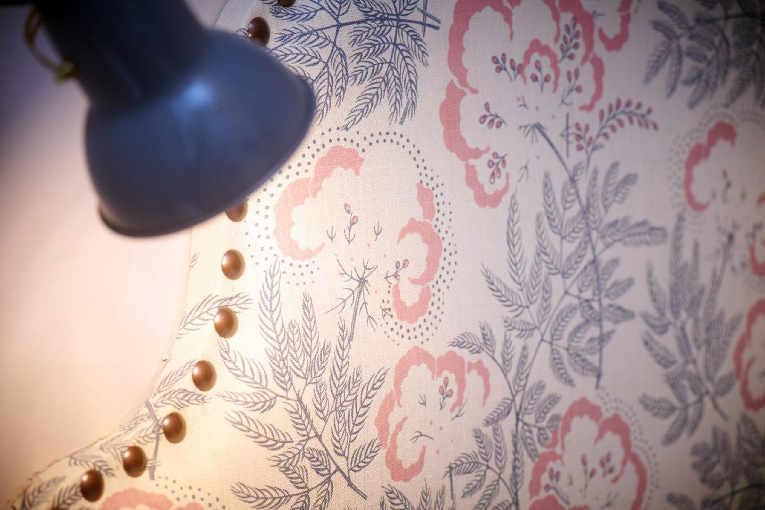 Detalle de una tela estampada con motivos florales y una lámpara.
