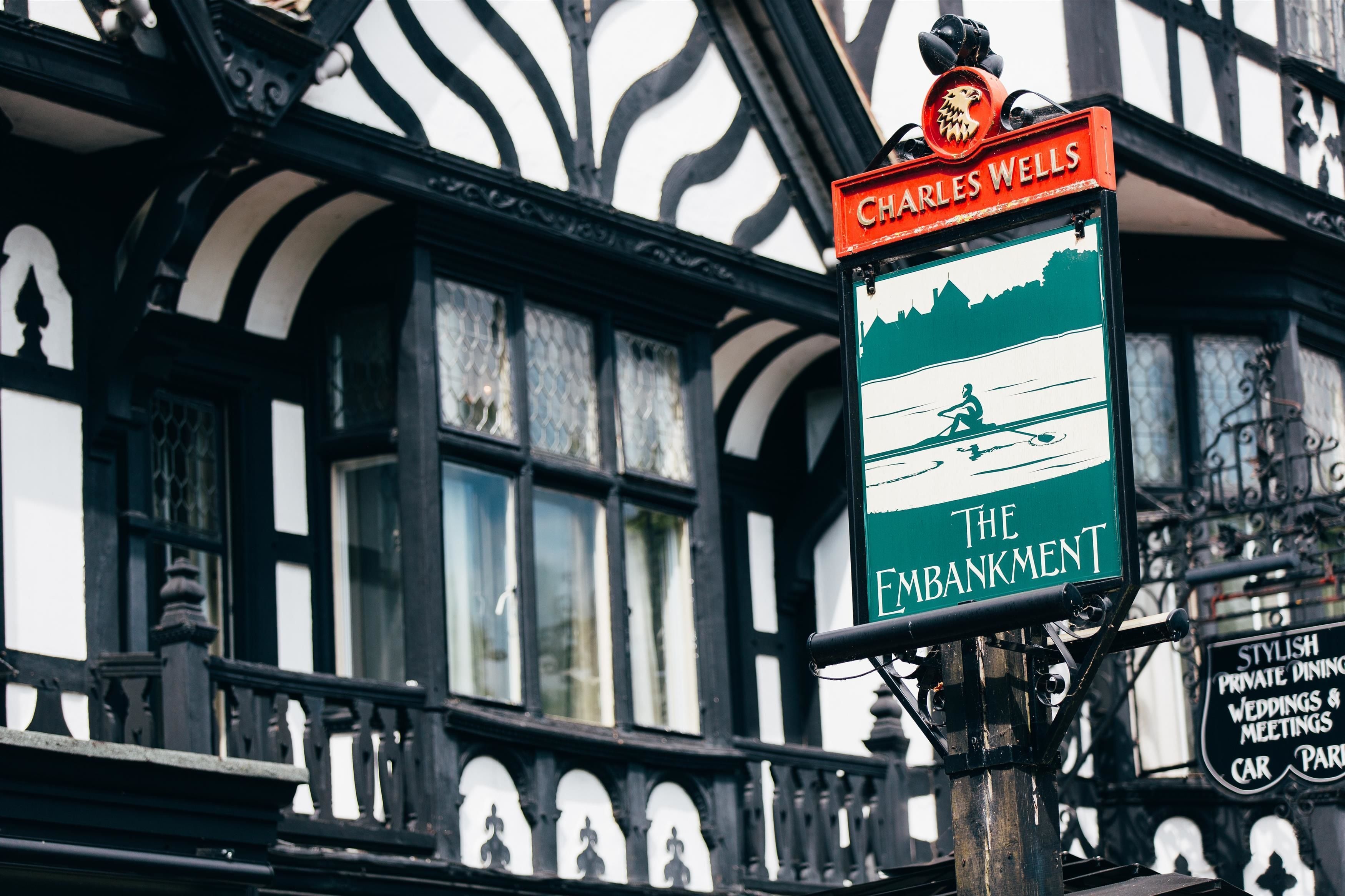 A traditional pub sign with a green background and a silhouette of a man rowing a boat.