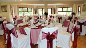 A banquet hall with round tables set for a formal event, adorned with white tablecloths and red sashes. - Wharton Park Golf & Country Club (Bewdley)