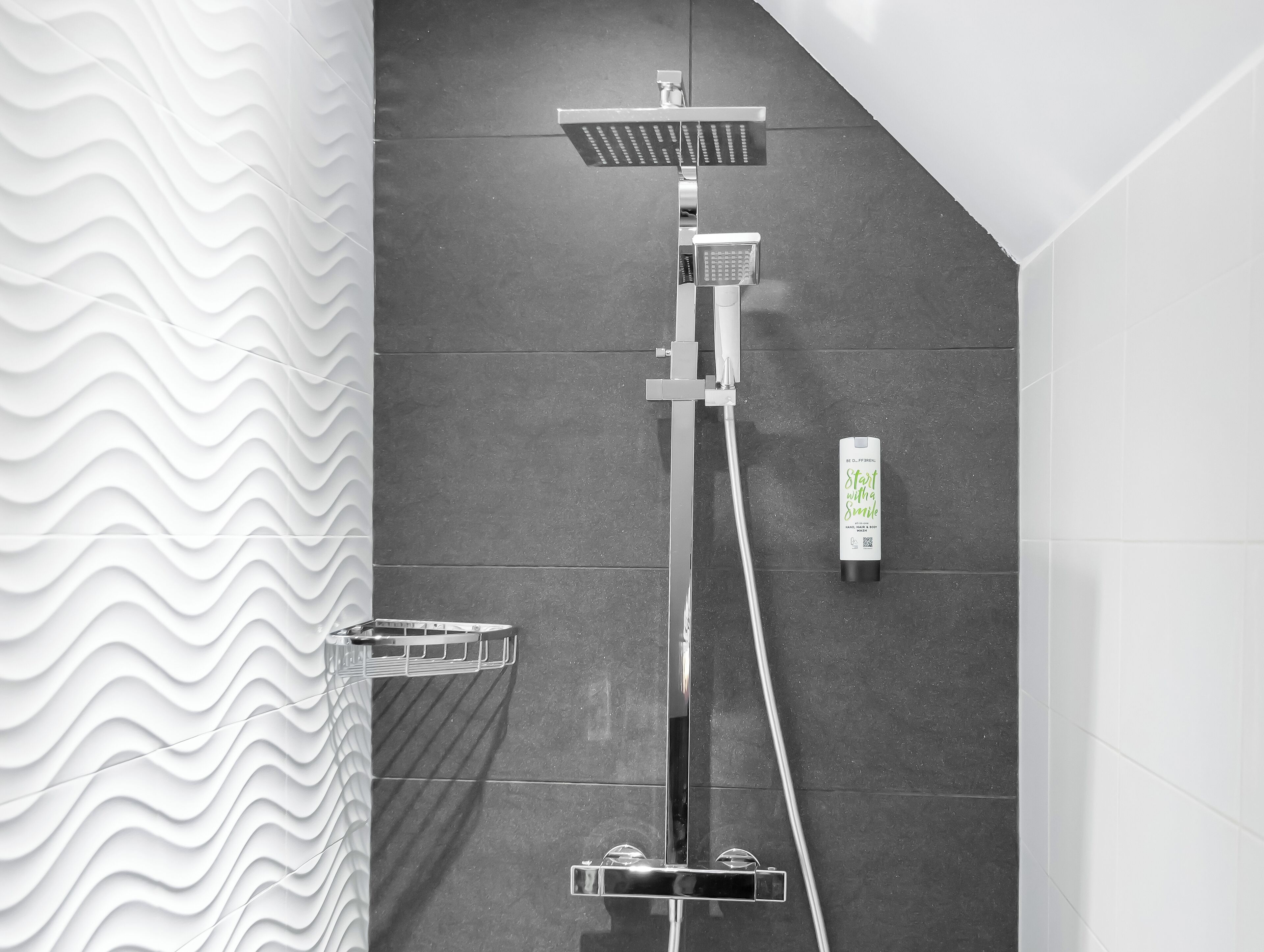 A modern shower with a rain showerhead, handheld showerhead, and a handheld soap dispenser.