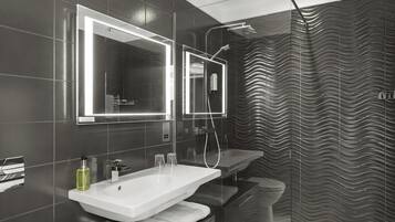 A modern bathroom with a large mirror, a sink, and a shower.