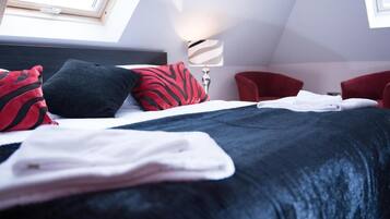 A modern hotel room with a neatly made bed, a red chair, and a lamp.
