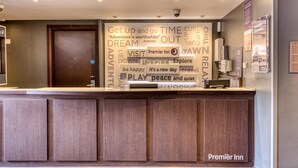 A hotel reception desk with a large sign featuring motivational phrases and the Premier Inn logo. - Premier Inn Birmingham South - Rubery (Birmingham)