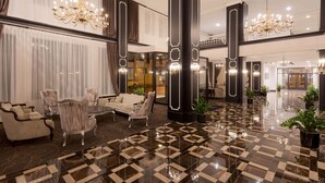 Un'ampia hall con pavimento a scacchi, arredi eleganti e lampadari.