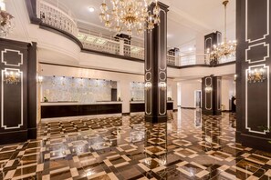 A spacious lobby with a checkered floor, large chandeliers, and a high ceiling. - Ramada Plaza Fond du Lac (Fond du Lac)