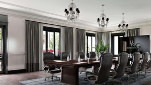 Una sala conferenze con un lungo tavolo, numerose sedie, un lampadario e un grande schermo.