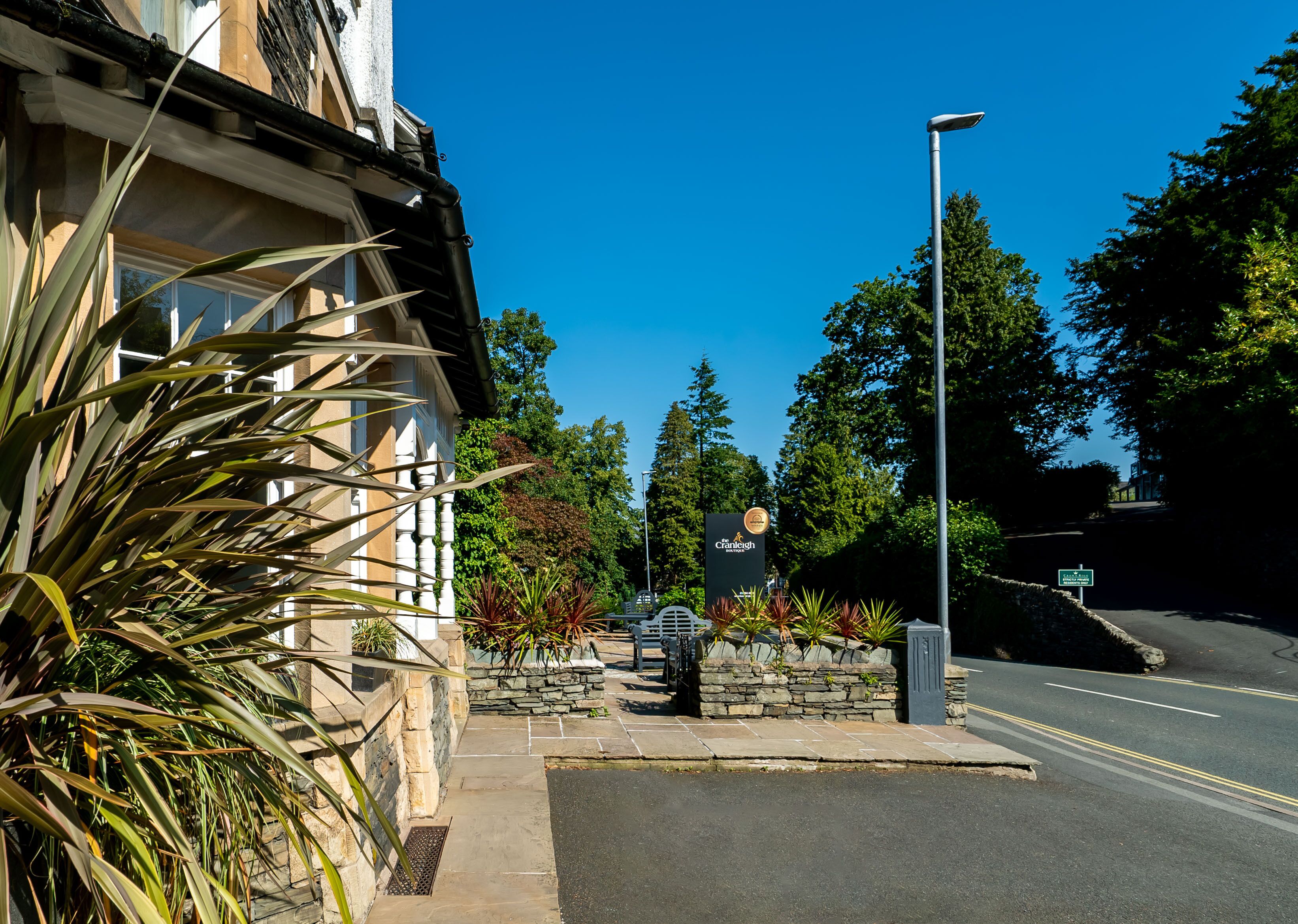 A street view with a building featuring a stone facade and a signboard.