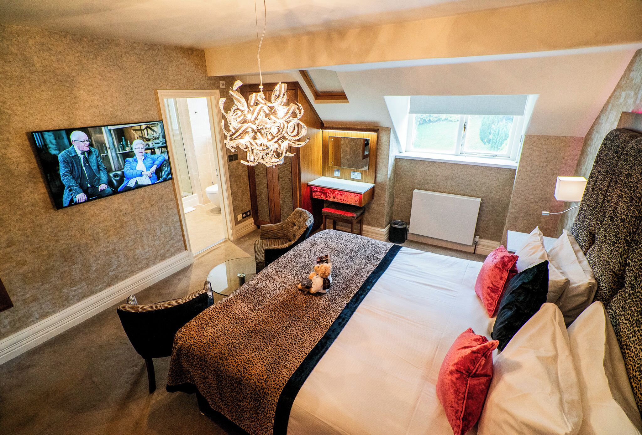 Une chambre avec un lit, un téléviseur fixé au mur, un bureau et une chaise.