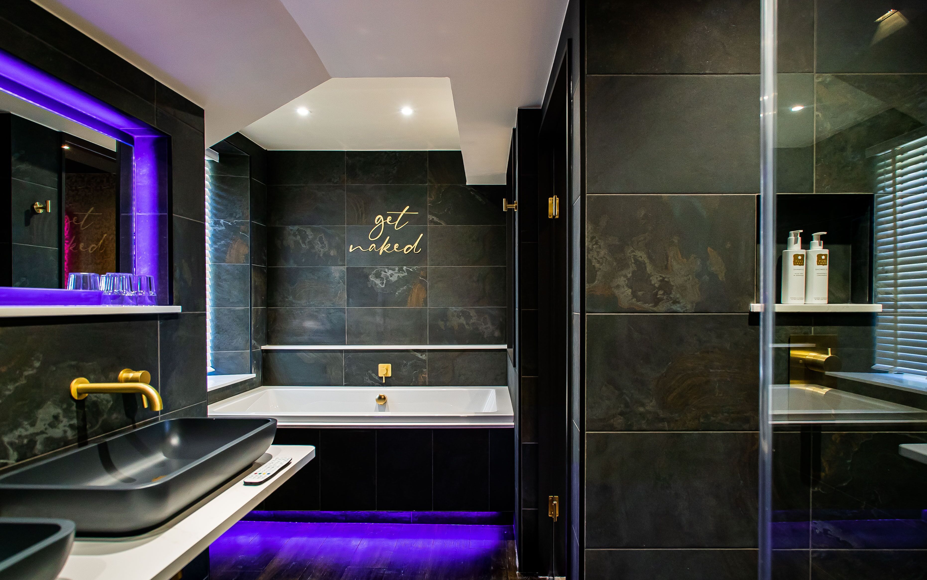 A modern bathroom with a large mirror, a white sink, and a bathtub.